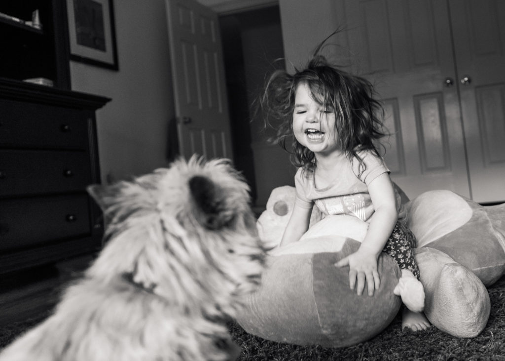 toddler laughing and jumping on monkey