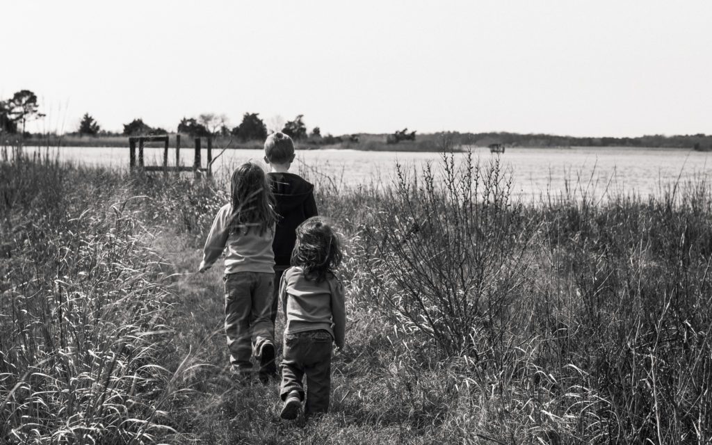 brother and younger sisters walking through march on Eastern Shore