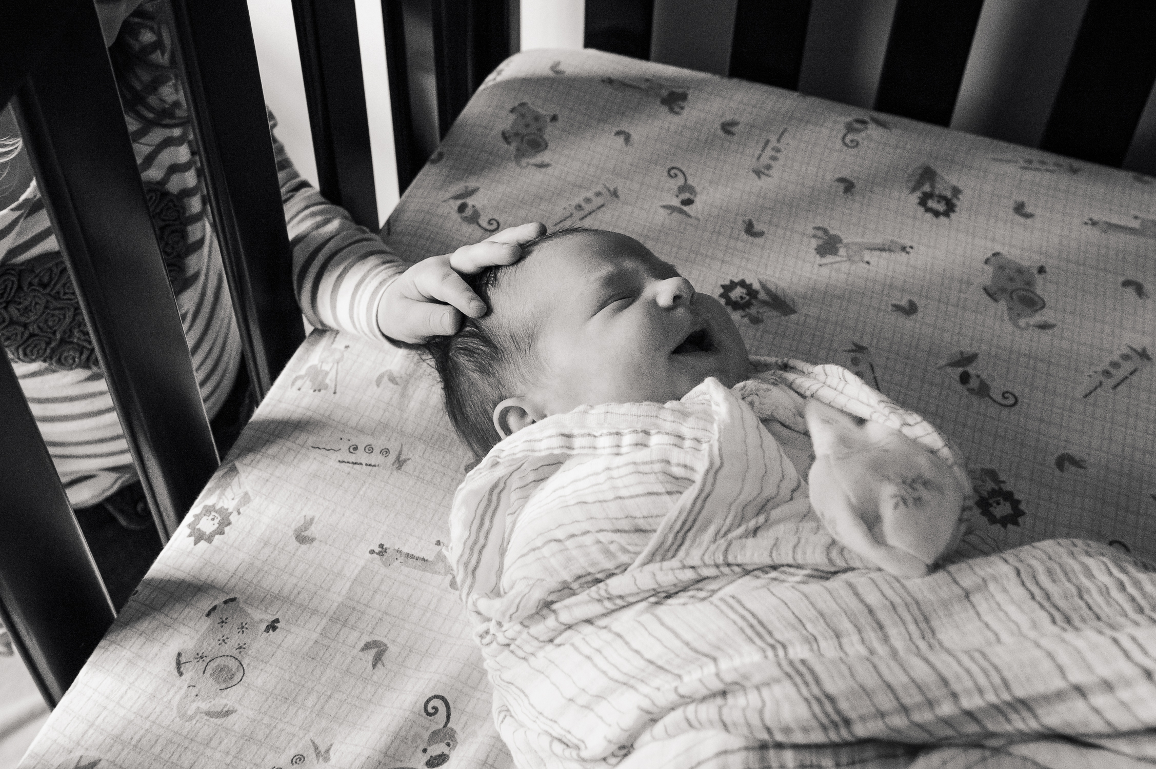 Sister Comfort big sister patting baby's head in crib