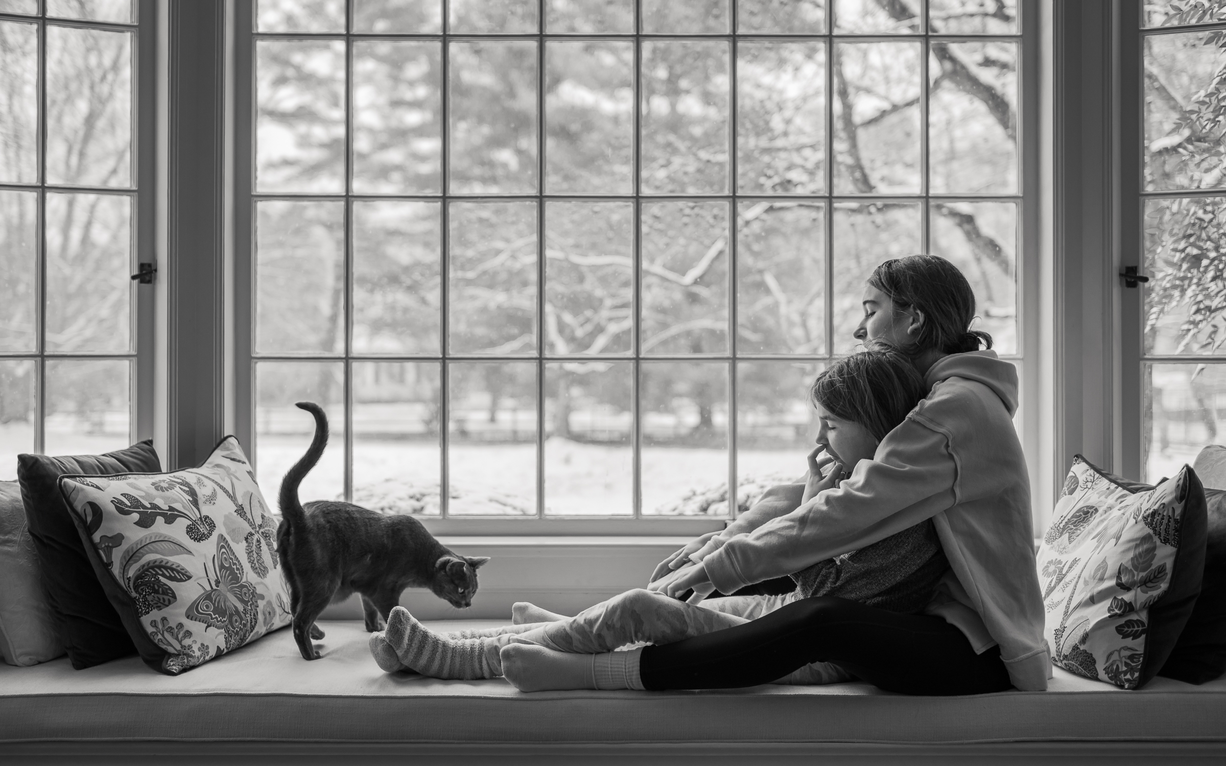 growinghumans-3 sisters and cat inside on a snowy day